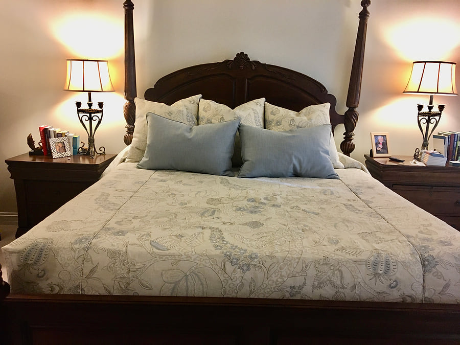 A four-poster bed dressed with custom bedding and cushions