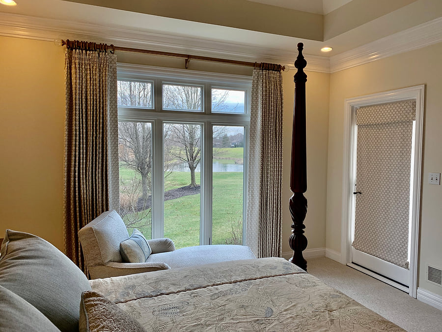 A bedroom window with draperies and a view across open ground